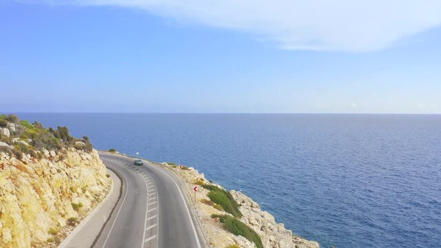 Aerial landscape of coastline and a road seascape. Cars drives down the asphalt road running along the sunny Mediterranean shoreline of Turkey. Aerial view 4K.