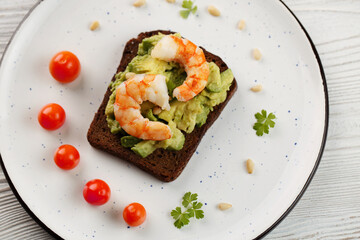 Toast with shrimp, avocado, nuts, tomatoes, parsley on plate