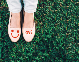 Woman feet in shoes with love and smile sign on the ground