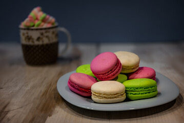 A cup of marshmallows and a plate of macaroons