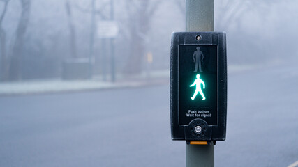 UK traffic crossing with Green man Illuminated on a cold foggy day