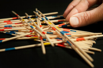 The family plays the popular board game Mikado, up close, the photo shows the father's hand as he...