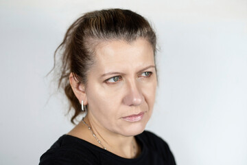 Portrait of a middle-aged woman on a light background, a woman is worried that the years fly by and she unfortunately does not get younger but older, her hair begins to turn gray