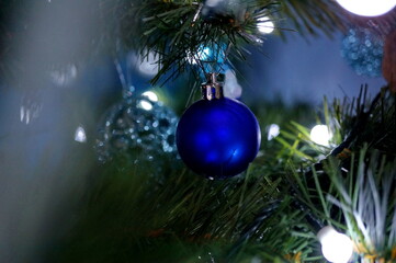 Obraz na płótnie Canvas Beautiful blue christmas ball hanging on the branch of a christmas tree