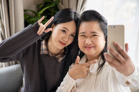 Lovely asian senior mother and young daughter taking smartphone photo selfie with happy family life, single mom, togetherness concept