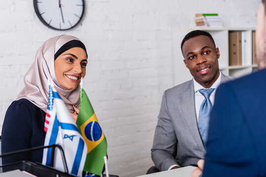 smiling african american and arabian business partners looking at interpreter on blurred foreground - Powered by Adobe