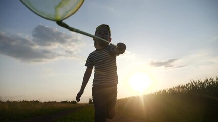 child run catching butterflies with a butterfly net in the park. happy family kid dream concept. boy run happy in the park with butterfly net silhouette. kid and fun butterfly net dream