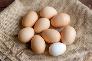 Rustic chicken eggs on burlap, top view.