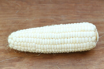 Close up single isolated white corn (peeled can see inside) on brown wood table background
