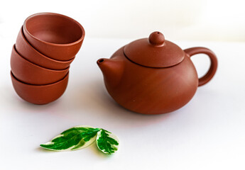 Terracotta teapot and cups on white background