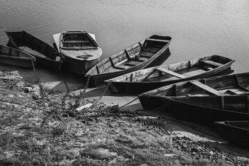 Wooden authentic old boats on the river bank. Life in the village of ordinary people. Transport and fishing vehicle. Black and white photo.