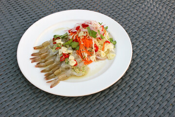 Authentic Asian Food: Plate of raw shrimps in fish sauce with fresh salad vegetables including red chili, garlic, carrots, onions and herbs.
