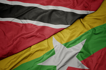 waving colorful flag of myanmar and national flag of trinidad and tobago.