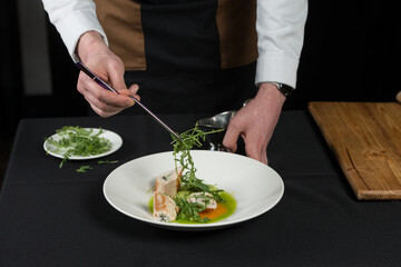 The chef prepares a serving of meatloaf. Putting Arugula over the dish