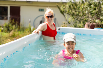 Mother and daughter playing together in home pool