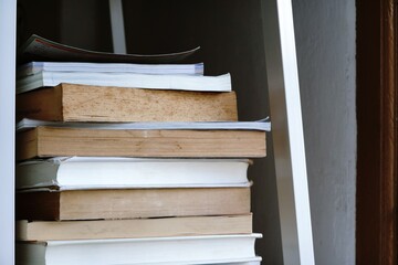 Side view of many old books stacked on the bookshelf after read.