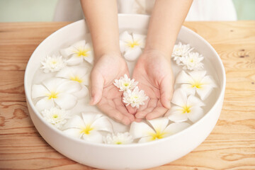 Fototapeta na wymiar Spa treatment and product for female feet and hand spa. white flowers in ceramic bowl with water for aroma therapy at spa.