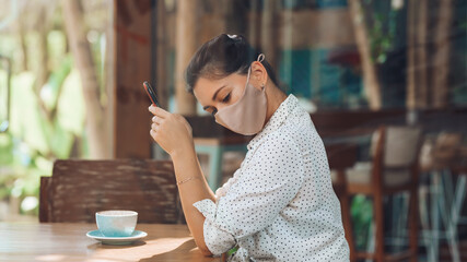 A girl sits at a table with a phone in a silk mask