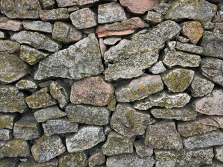 Old grey stone wall of different size bricks