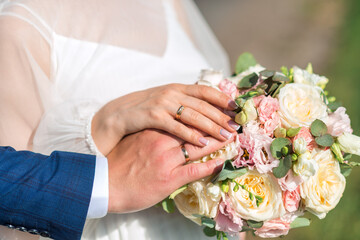 Obraz na płótnie Canvas newlyweds ' hands with rings. Wedding bouquet on the background of the hands of the bride and groom with a gold ring