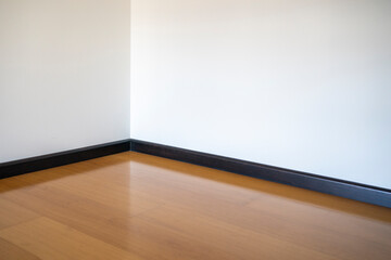 Empty room with wooden floating laminate flooring. House interior, wide bedroom or living room space. Newly recently painted new apartment or house. Wood floor. Real state and property management