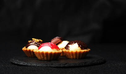 Selective focus of red topping cheese tart with other homemade cheese tart on slate plate