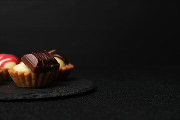 Selective focus of homemade chocolate cheese tart on slate plate on dark background.