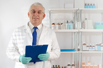 Doctor senior man in medical apparel holding clip-folders  in the hospital.