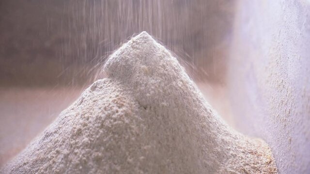 Wheat or rye flour is poured from the mill into a large pile. Production of flour in a bakery for baking bread.