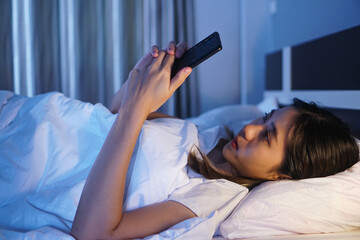 Obraz na płótnie Canvas woman using smartphone on bed at night , tired addictive can’t sleep, playing entertainment internet browsing social media website business, domestic home comfy lifestyle