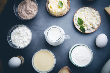 Fresh dairy products, milk, cottage cheese, eggs, yogurt, sour cream and butter on black background, top view