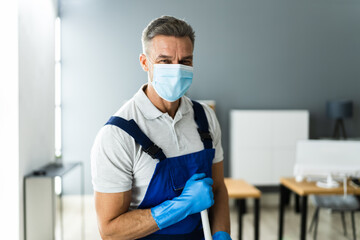 Fototapeta na wymiar Male Janitor Mopping Floor In Face Mask