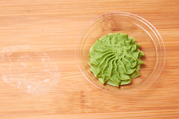 Bowl with wasabi on wooden background, top view. copy space.