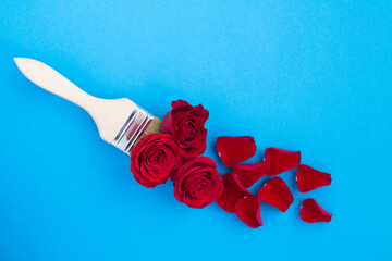 Top view of paintbrush with red roses on the blue surface