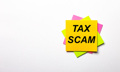 On a light background - bright multicolored stickers with the text TAX SCAM. Copy space