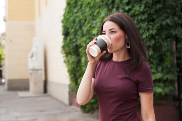 Obraz premium beautiful brunette drinking coffee on the street in the summer