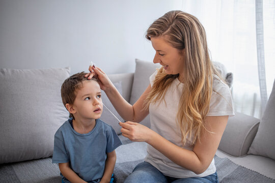 Small Boy Having A Rapid COVID-19 Test At Home During Coronavirus Pandemic. Mother Takes A Cotton Swab Coronavirus Test From Child Nose To Analyse If Postitve For Covid-19.