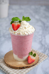 Strawberry smoothie with yogurt topped on whipping cream in glass plastic.