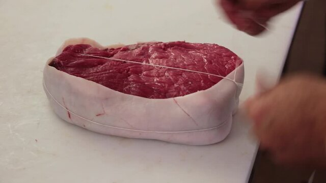 Bardage et le ficelage d'un rosbif coup&eacute; dans l'aiguillette de rumsteak. 