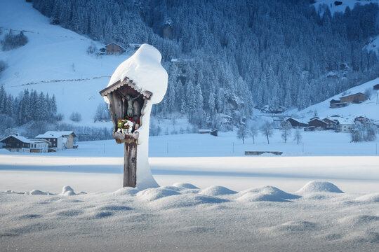 Eingeschneites Marterl in einer verschneiten Landschaft am Wanderweg