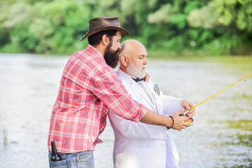 retire his experience. family, granddad and drandson fishing. two fishermen with fishing reel. hobby and recreation. retired businessman. male friendship. mature man fisher celebrate retirement