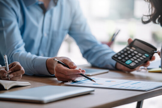 Businessman Pointing Graph And Using Calculator During A Business Meeting.