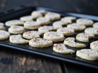 Raw shortbread cookies, sprinkled with sugar, on a baking sheet from the kitchen oven on a dark wooden table.Confectionery background.