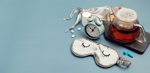 Classic alarm clock, sleeping mask, tea pot on blue pastel background.  Minimal concept of rest, quality of sleep, good night, insomnia, relaxation. - obrazy, fototapety, plakaty