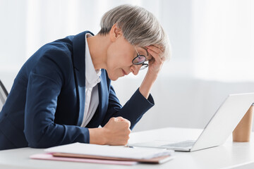 exhausted middle aged businesswoman suffering from headache in office