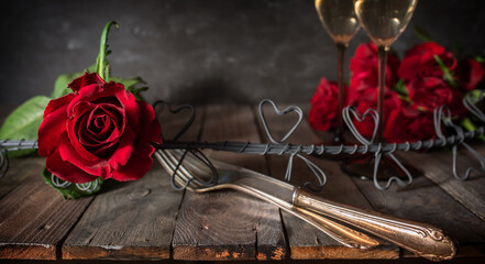 Decoration for a romantic dinner with roses and champagne on rustic wooden table. Background with...