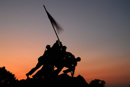 The US Marine Corp Memorial, in Arlington, Virginia, is silhouetted against the sky.  The sculpture recreates soldiers planting a flag on Iwo Jima