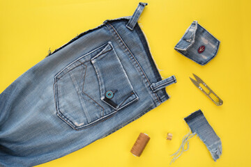 Remake of old vintage jeans. Sewing a style sundress from husband's retro jeans. Yellow background. Reuse, zero waste concept. Top view. Stock image.