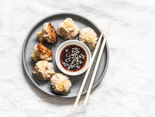 Pork wontons fried with sesame seeds and soy sauce on a light background, top view
