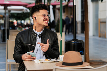 handsome guy having breakfast and listening to music in a cafeteria